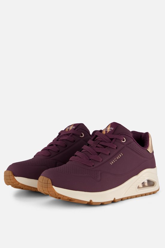 Paar paarse Skechers sneakers met beige zolen en gouden details.