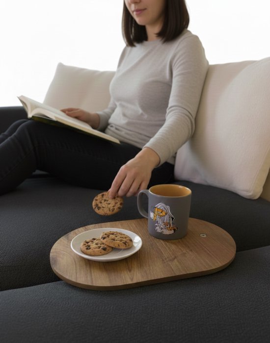 Houten dienblad op een donkere bank met een vrouw die een boek leest en een mok.