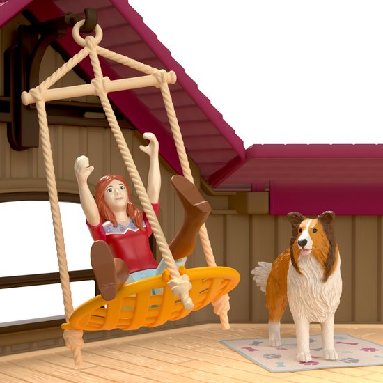 Meisje met rood shirt op schommel, met een sheltie hond naast haar.