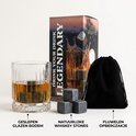 Een glas met whiskey, natuurlijke whiskey stones en een zwart opbergzakje naast een doos.