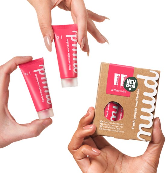 Handen tonen twee roze tubes nuud natural deodorant en een bruine verpakking met "NEW CREAM" logo.