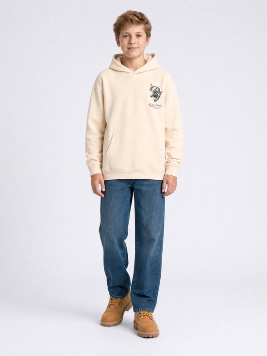 Jongen in crèmekleurige hoodie, blauwe jeans en bruine schoenen, met kraan-print op de borst.
