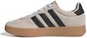 Beige Adidas sneakers met zwarte strepen, gumkleurige zool en zwarte hiel.