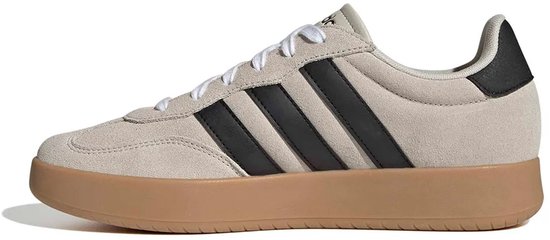Beige Adidas sneakers met zwarte strepen, gumkleurige zool en zwarte hiel.