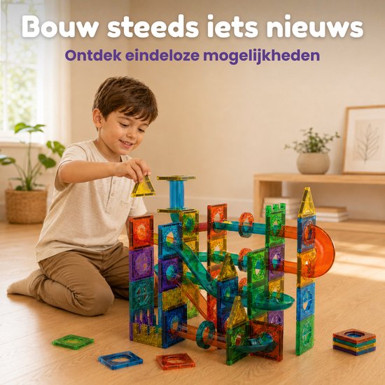 Jongen bouwt met veelkleurige magnetische tegels, waaronder buizen en hellingen, om een knikkerbaan te maken.