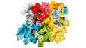 Une pile de briques LEGO Duplo aux couleurs de l'arc-en-ciel avec une voiture rouge, des figurines, un toboggan et une maison de jeu.
