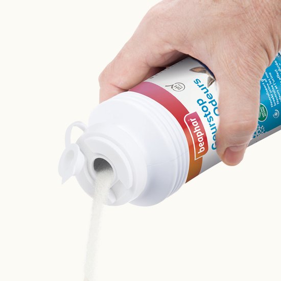 Hand die witte geurkorrels uit een open blauwe fles schenkt.