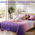 Een vrouw slaapt onder een paars, roze en oranje gradiënt dekbed in een lichte slaapkamer. Inclusief bijpassende kussensloop.