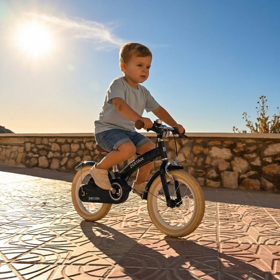 Petit garçon sur un vélo enfant Deryan bleu foncé avec pneus beiges.