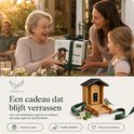 Houten vogelvoederhuisje met camera, met een koolmeesje dat eet. Een smartphone toont de koolmees in de nachtmodus.