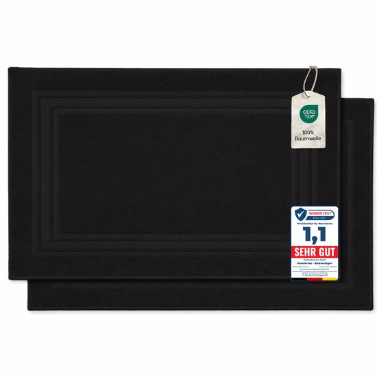 Twee zwarte badmatten met OEKO-TEX certificering. De bovenste mat heeft een label met "100% Baumwolle".