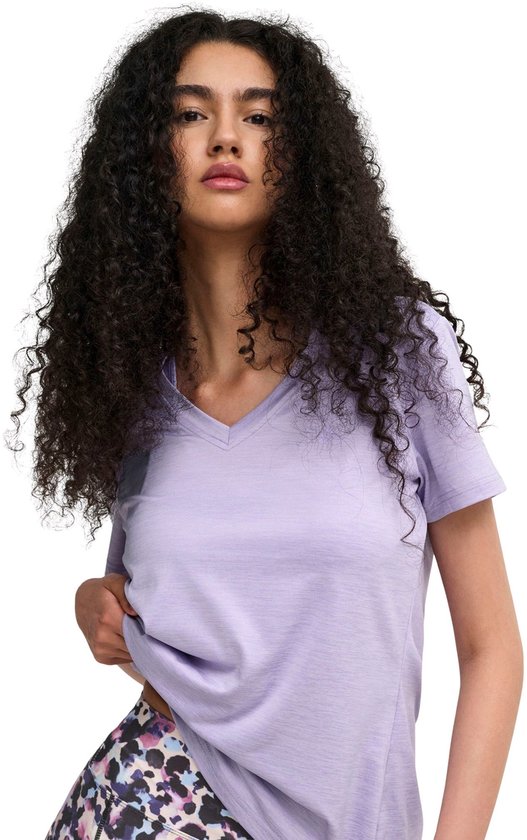 Model draagt een lichtpaars V-hals T-shirt en een legging met veelkleurig abstract patroon. Close-up van voren.