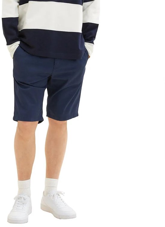 Model draagt een donkerblauwe chino korte broek met een gestreept shirt.