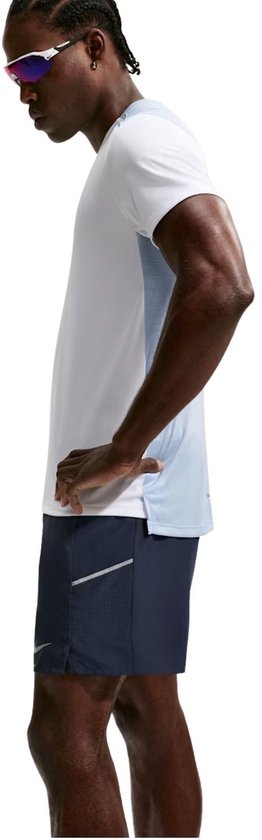 Man met marineblauwe Nike hardloopbroek en witte t-shirt met lichtblauwe panelen.