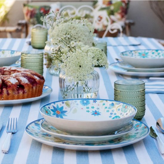 Groene glazen met bobbelig reliëf op een buitentafel met gebak, bloemen en blauw gestreept tafelkleed.