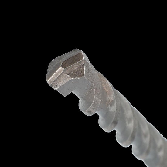 Close-up van de hardmetalen kop van een boor, geïsoleerd op een zwarte achtergrond.
