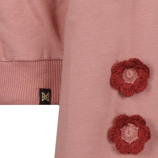 Detail van roze hoodie met gebreide rode bloemen op de mouw en label.