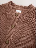 Detail van de halslijn van een bruin gebreid babyvest met knopen.