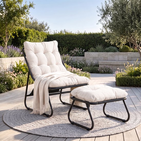 Fauteuil gris clair avec coussin côtelé en velours côtelé sur un cadre en métal noir, avec pouf assorti, sur un tapis rond gris dans un jardin.