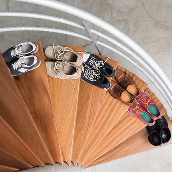 Bovenaanzicht van diverse schoenen op een houten spiltrap.