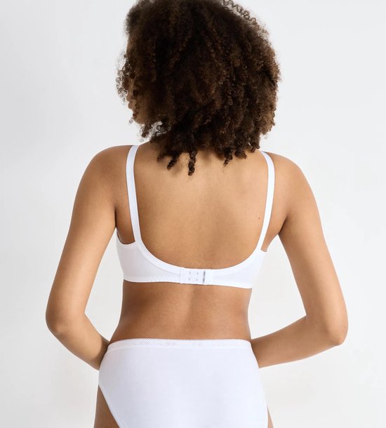 Achterkant van een witte Sloggi beha zonder pads, gedragen door een vrouw met krullend haar.