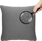 Grijze teddy bouclé kussen, met vergrootglas dat de textuur van het oppervlak toont.