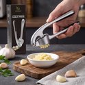 Hi Nature knoflookpers, zilverkleurig metaal, wordt gebruikt om knoflook te persen boven een wit schaaltje.
