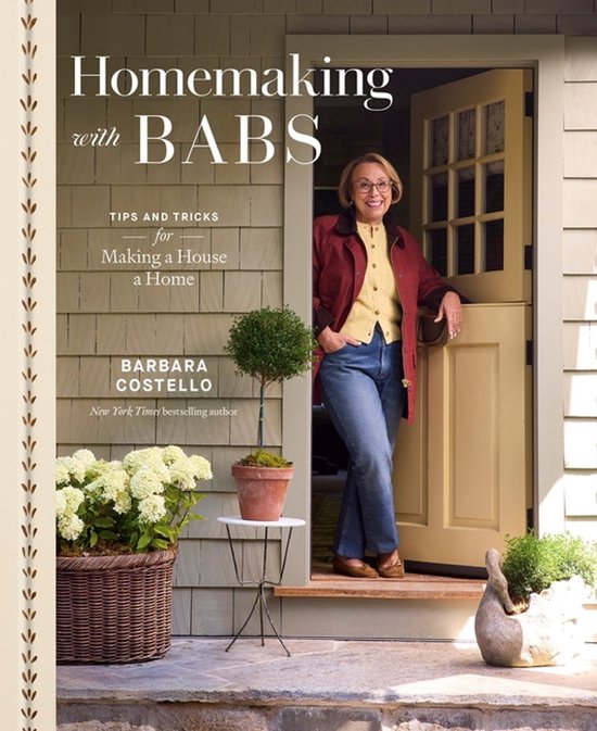 Boek "Homemaking with Babs" van Barbara Costello. Een vrouw staat lachend bij een open deur, met hortensia's en een boompje ernaast.