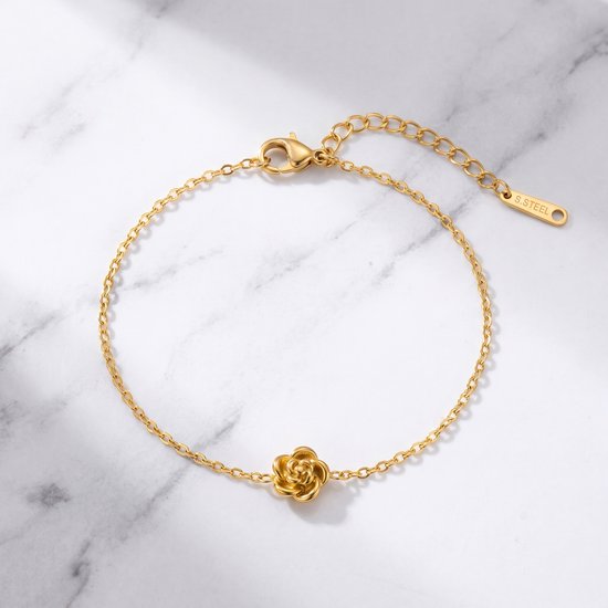 Gouden armband met roosje en karabijnsluiting, op marmeren achtergrond.