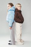 Twee kinderen staan rug aan rug in pufferjassen; één in bruin, één in lichtblauw.