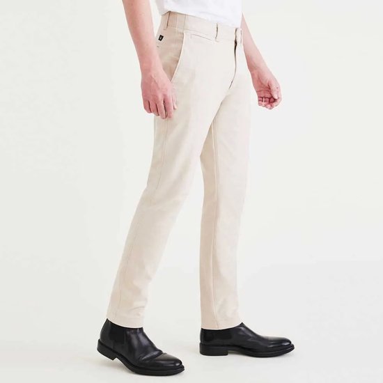 Man in beige chino broek met zwarte schoenen. Zichtbaar is de zijkant van de broek.