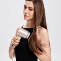 Vrouw met lang, steil bruin haar droogt haar haar met de champagnekleurige Laifen haardroger.