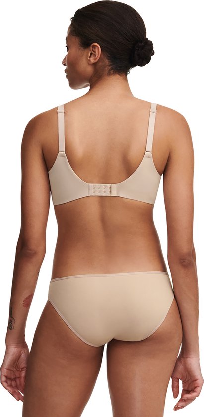 Model draagt een beige bh en slip van achteren gezien. De bh heeft een haaksluiting.
