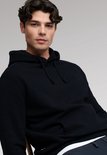Close-up van model met donkerblauwe hoodie, de capuchon omhoog.