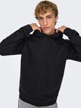 Man met blonde haren trekt aan de capuchon van een zwarte hoodie met kangoeroezak.