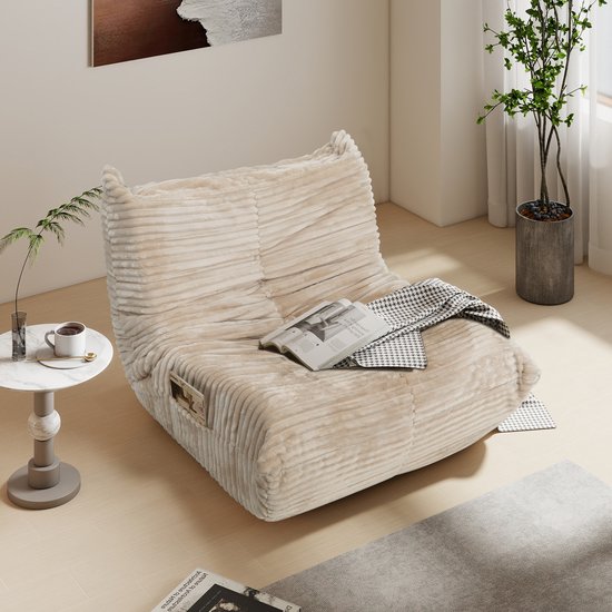 Een beige zitzak met geribbelde stof, met een tijdschrift en plaid erop, in een modern interieur.