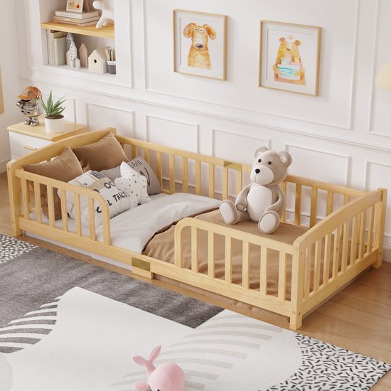 Houten kinderbed met vrolijke kinderillustraties en teddybeer, naast een nachtkastje en speelgoed. Natuurlijke houtkleur.
