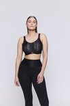 Model in een zwarte sportbeha met geometrische print en zwarte legging.