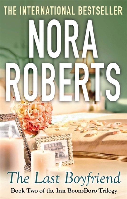De internationale bestseller "The Last Boyfriend" van Nora Roberts, met een romantisch boeket bloemen en kaarsen op een bed.