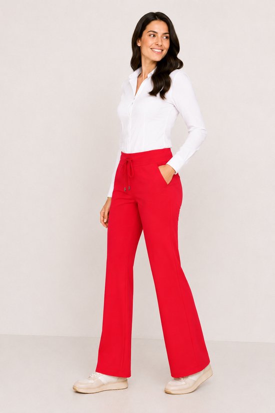 Model met witte blouse en rode flared broek met koord sluiting aan de voorzijde.