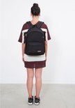 Femme portant un sac à dos Eastpak bleu foncé sur le dos, avec un haut à rayures.