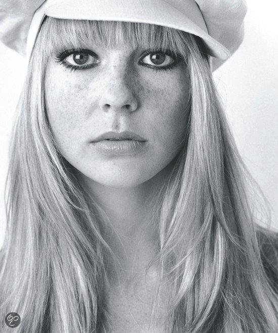 Model met lange blonde pony, sproeten en witte pet. Zwart-wit.