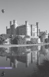 Leeds Castle, een groot stenen kasteel met torens, weerspiegeld in het water. Een luchtballon is zichtbaar.