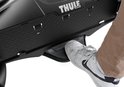 Voet die op de ontgrendelingshendel van de Thule fietsendrager drukt.