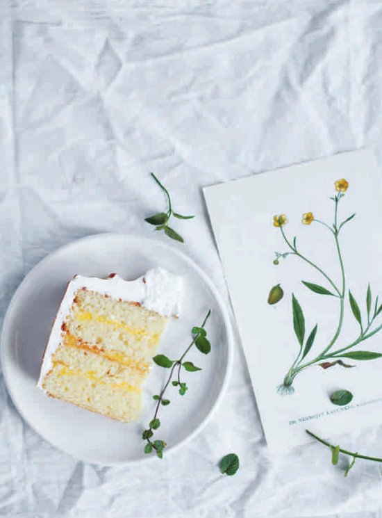 Een plak cake met witte glazuur en gele vulling, naast een botanische illustratie van een bloem.