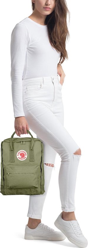 Vrouw in witte kleding draagt een kleine groene Fjallraven Kanken rugzak.