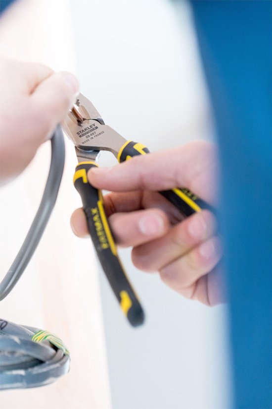 Handen gebruiken een Stanley FatMax combinatietang om een kabel te strippen.