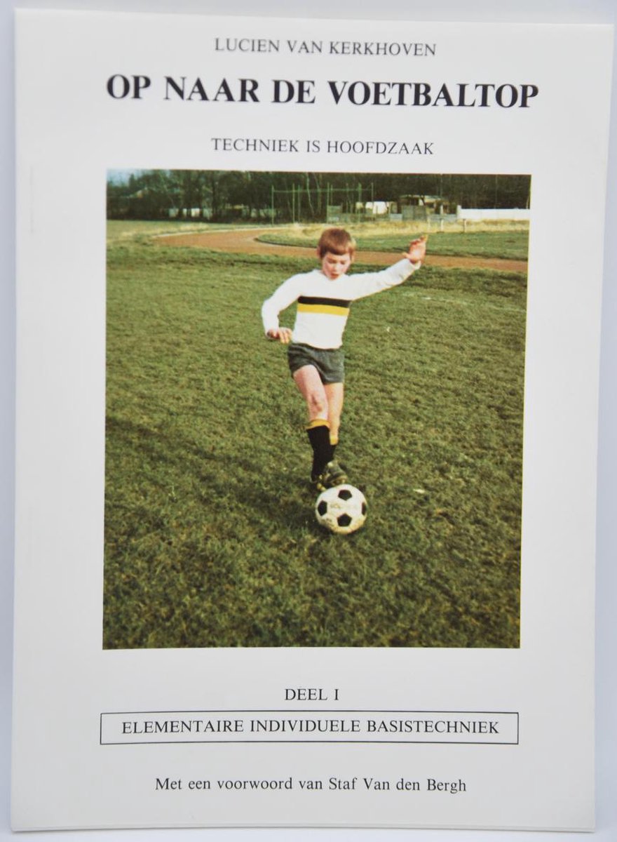 Jonge voetballer met wit shirt, gele strepen en grijs broekje, stapt over bal op grasveld.