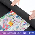 Close-up van een puzzelmat die wordt opgerold met een drukke puzzel van een stad, te zien is de tekst 'amazan'.
