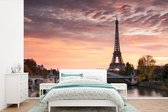 Behang - Fotobehang Een oranje lucht boven de Eiffeltoren in Parijs - Breedte 450 cm x hoogte 300 cm